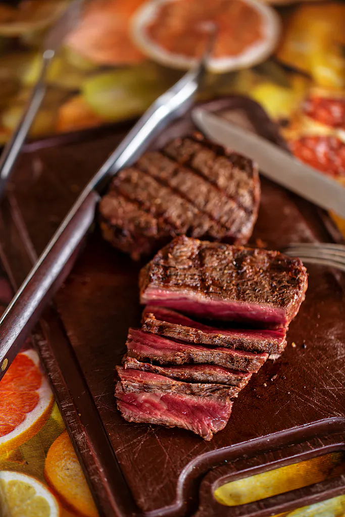Sliced medium-rare grilled steak on wooden cutting board