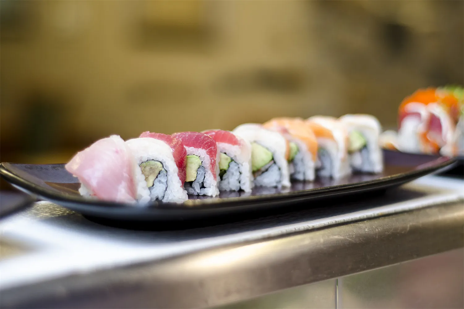 Assorted sushi rolls on a black serving plate