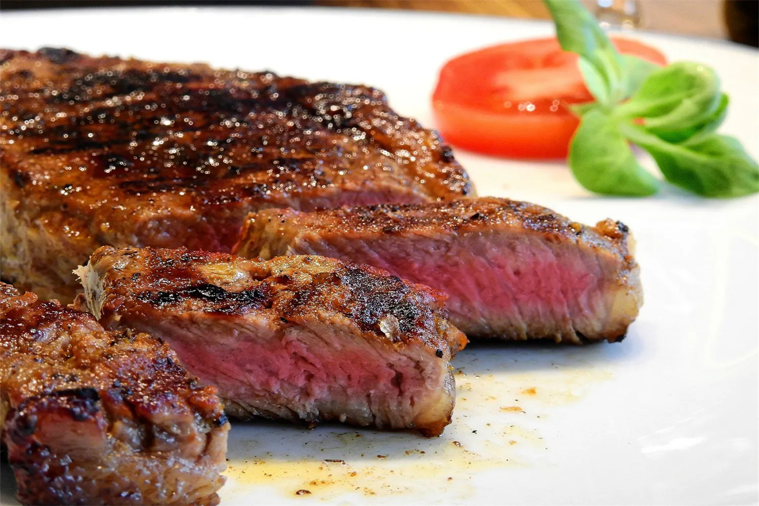 Sliced medium-rare grilled steak on a white plate